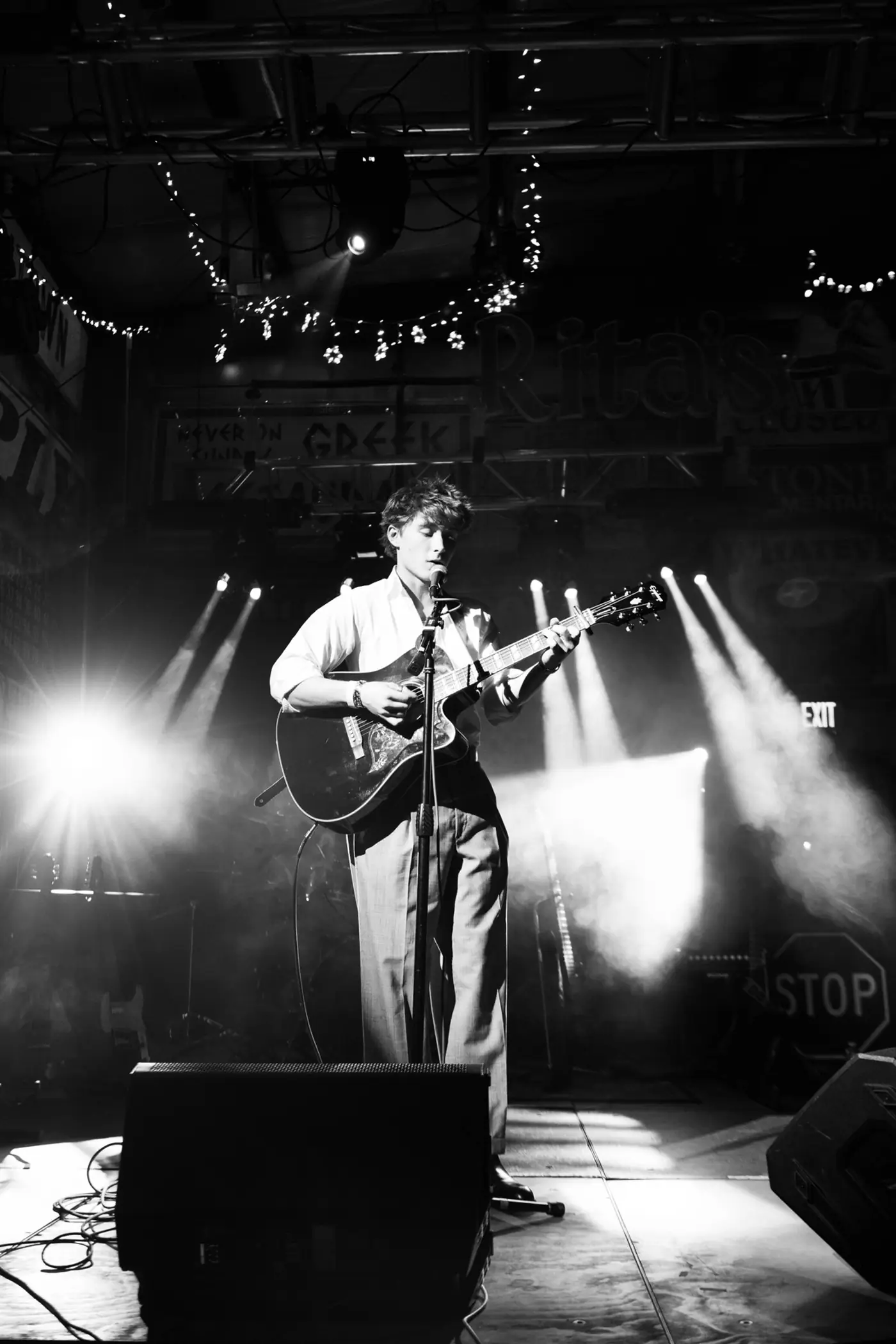 Cameron on stage in black and white, spotlights behind him