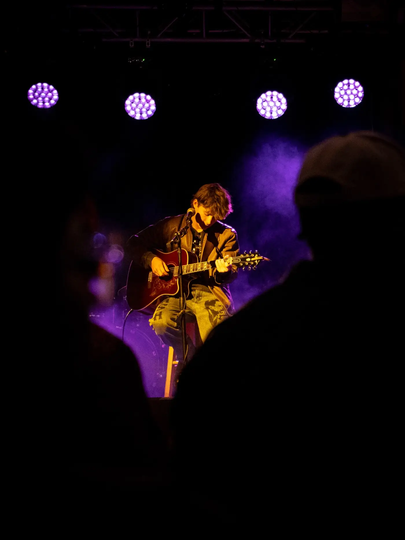 Cameron seen over the crowd under purple lights